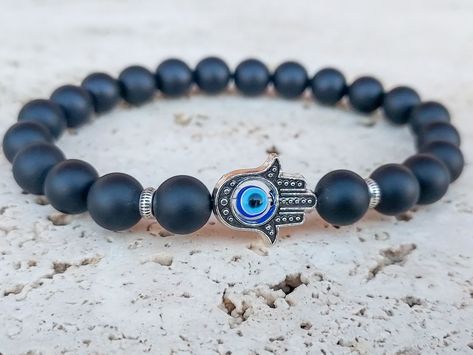 "Hamsa Hand Bracelet made for triple protection and good luck with using antique silver Hamsa Hand, Evil Eye bead and Black Onyx gemstone beads. The HAMSA is an ancient Middle Eastern amulet symbolizing the Hand of God. In all faiths it is a protective sign.  The word \"Hamsa\" means \"5\" and refers to the five fingers. The number 5 is a powerful number and symbolizes defence, power and fortune. Also represents blessings and strength, and is seen as potent in deflecting the evil eye. It brings it's owner happiness, luck, health, and good fortune. BLACK ONYX Protection, Encouragement, Strength, Happiness, Good Luck, Removes Negativity, Healing Primary Chakras: Root EVIL EYE - an eye-shaped amulet believed to protect against the evil eye Perfect good luck and protection men's gift for any o Evil Eye Bracelet For Men, Evil Eye Spiritual, Eye Spiritual, Hand Evil Eye, Black Onyx Bracelet, Hand Bracelet, Onyx Bracelet, Cotton Gifts, Onyx Gemstone