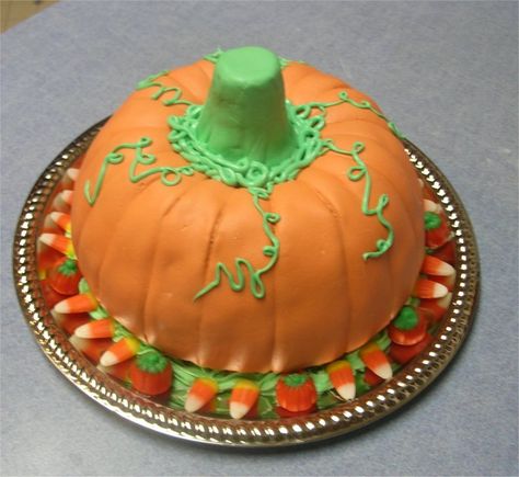 Pumpkin Cake - This is my 2nd cake I've made. it is for a cake walk at our Fall Festival at my church ..  Spice cake made in a bundt pan turned upside down to make a pumpkin shape ( I don't have the pumpkin cake pan)  Covered it with homemade marshmallow fondant and green bc. Stem is made with an ice cream cone covered in green mmf.. Placed candy around the bottom of the cake. Upside Down Pumpkin Cupcake Cones, Bundt Cake Pumpkin Decorated, Pumpkin Surprise Cake, Bundy Cake Pumpkin, Pumpkin Decorated Cake Ideas, Candy Corn Cake Decoration, Pumpkin Shaped Cake, Halloween Pumpkin Cake, Nothing Bundt Cakes