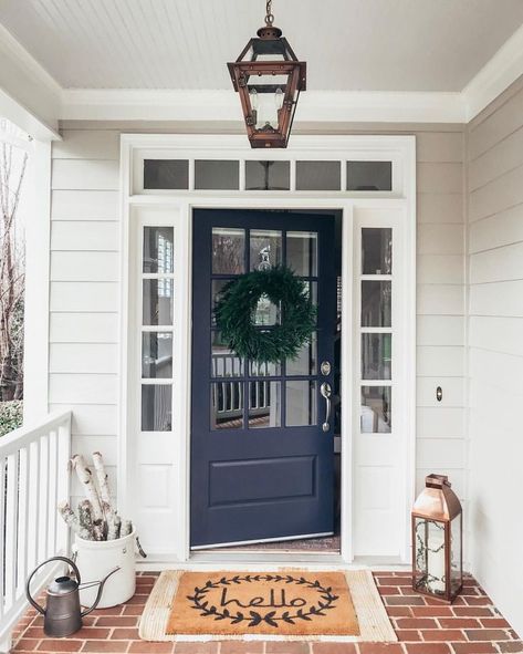 Navy blue front door. Southern front porch inspiration with navy blue front door and a hanging copper lantern by Primo. Sherwin Williams Misty SW 6232 blue porch ceiling, Pearly White trim SW 7009, Charcoal Blue front door SW 2739, and Benjamin Moore Revere Pewter siding HC-172. Wayfair faux cedar wreath and Hello doormat. #winterporchdecor #frontdoor #navyfrontdoor #frontporch #reverepewter #exteriorcolorpalette #blueporchceiling #copperlantern #charcoalblue Navy Blue Front Door, Navy Front Door, Blue Porch Ceiling, Front Porch Inspiration, Yellow Front Doors, Blue Front Door, Front Door Paint Colors, Door Paint Colors, Painted Front Doors