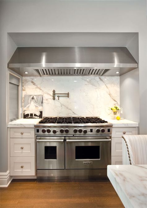 Gorgeous kitchen boasts cooking alcove filled with stainless steel hood suspended over Wolf Range flanked by cabinets topped with with marble paired alongside satin nickel swing-arm pot filler mounted on white marble backsplash. Toronto Home, Kitchen Hood, Fridge Decor, Residential Architect, Diy Countertops, Marble Counter, Laminate Countertops, Kitchen Farmhouse, Transitional Kitchen