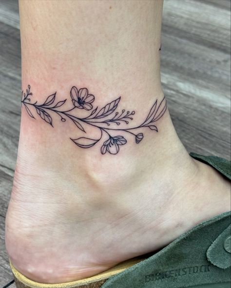 Super cute wrap around ankle vine! #ankletattoo #wraparound #wraparoundtattoo #wraparoundankletattoo #tattoos #linework Flower Vine Ankle Tattoo, Ankle Tattoo Wrap Around, Wrap Around Leg Tattoo, Ankle Wrap Tattoo, Wrap Around Ankle Tattoos, Tattoo On Ankle, Leg Band Tattoos, Wrap Around Tattoo, Around Arm Tattoo