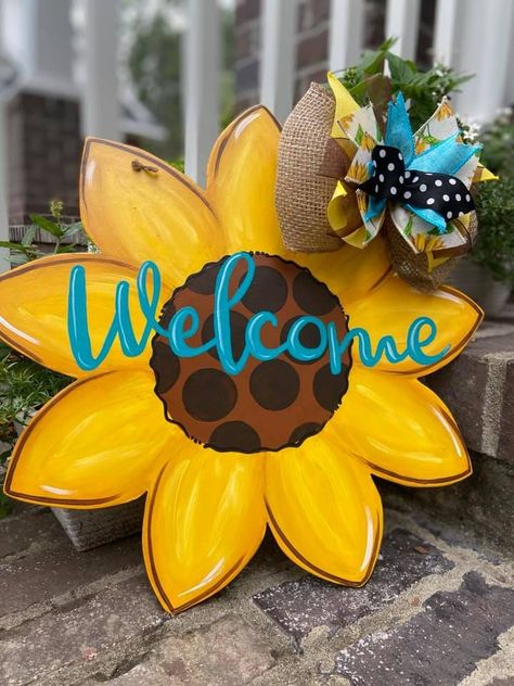 "Sunflowers are perfect for spring, summer, or fall.  Hand painted with acrylic paint on wood, and sealed with a clear coat for protection.  Due to the handmade nature of this product, slight imperfections may occur.  To prolong the life of your door hanger, it is best to display under a covered porch or inside.  Avoid direct contact with rain. Door hangers can be personalized with your last name or some other kind of greeting, just type what you would like in the \"personalization\" section whe Sunflower Things, Diy Storage Trunk, Sunflower Door Hanger, Rustic Tableware, Profitable Crafts, Welcome Flowers, Hanger Ideas, Fall Decor Diy Crafts, Wood Door Hanger