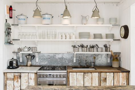 The kitchen is brilliantly simple, with cupboard doors made from boards salvaged from an original ceiling in the house. The white-painted shelves are scaffolding boards. The splashback is galvanised steel and the lights are from Pale & Interesting. The kitchen table provides another preparation area European Country Kitchen, Dapur Rustic, Kitchen Open Shelves, White Cabin, Country Kitchen Designs, Rustic Kitchen Cabinets, Kabinet Dapur, Farmhouse Kitchen Cabinets, Cottage Design