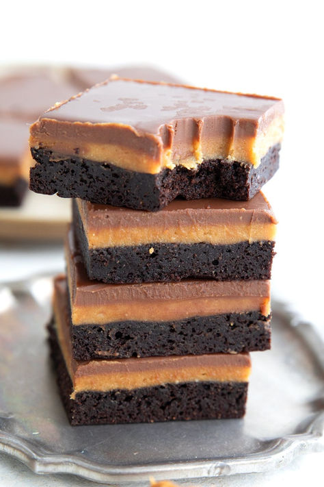 A stack of low carb peanut butter brownies with a bite taken out of the top one. Keto Peanut Butter Squares, Paleo Peanut Butter Brownies, Keto Peanut Butter Bars Almond Flour, Sugar Free Peanut Butter Fudge, Keto Chocolate Peanut Butter Fudge, Keto Peanut Butter Chocolate Bars, Keto Peanut Butter Brownies, Peppermint Brownies Recipe, Peanut Butter Brownies Recipe