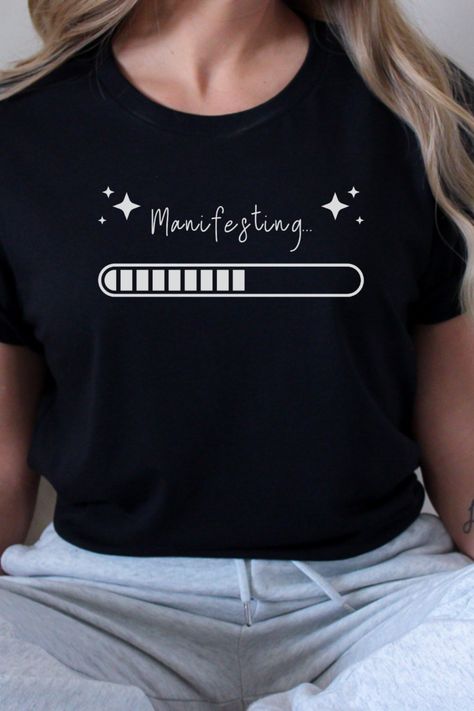 Plain tee with the word "manifesting" surrounded by 4 point stars, and a progress bar that shows 50% completion. Recovery Shirts, Bar Shirt, Spiritual Shirts, Good Energy, T Shirts With Sayings, Manifestation Quotes, Unique Tshirts, Fabric Painting, Shirts With Sayings