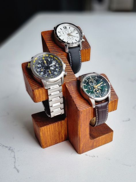 Wooden watch display stand. Elegant way to exhibit your watches. Handmade out of solid wood and stained to create rustic finish. Perfect gift idea for a watch enthusiast who likes to put their prized possessions on show.  Top part is designed to rest the watch case on the angle in a very presentable position. This is also very functional for the solar powered watches that should not be stored away.  Stand is crafted from solid pieces of timber therefore natural imperfections like knots may be featured on the surface. These, if present will be purposely preserved and stained just like the rest of the stand to enhance the innate character of the product as well as achieve the rustic style. Two types of stands are available as standard: featuring two or three spaces (stand for more that three Watch Stand Design, Timber Jewellery Stand, Wooden Watch Holder, Wooden Watch Stand, Diy Watch Display, Watch Stand Diy, Wooden Key Holder Ideas, Diy Watch Holder, Watch Display Ideas