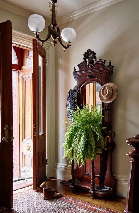 Historic brownstone entryway with original light fixture, doors, newel post, vintage area rug, and coat rack in a Boston home designed by Sarah Scales Victorian Home Hallway, Restoring A Victorian Home, Early 1900's Homes Interiors, Brownstone Entryway, 1920s Home Interior, Brownstone Renovation, Antique Entryway, Victorian Entry, Boston Brownstone