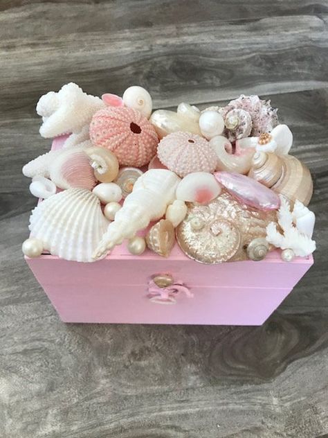 "This beautiful seashell jewelry box is a wonderful reminder of the beauty of the ocean! I started out with an adorable metal latched wooden box that I painted a shabby chic pale pink color. I then added a stunning cluster of white, cream, and pale pink seaside treasures on the lid: a white spindle shell, white ark, pearlized abalone, two pink sea urchins, a pink turbo, and a piece of white coral. Accenting the piece are some pretty white pearls and pearl umboniums. It is a gorgeous box to give Handmade Pink Shell As A Gift, Seashell Box Diy, Shell Box Diy, Wooden Box Painting Ideas, Shabby Chic Beach Decor, Diy Trinket Box, Seashell Jewelry Box, Mermaid Jewelry Box, Painted Seashell Jewelry Holder