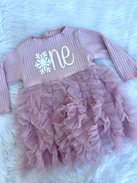 "This frilly dress will be darling on your sweet baby girl! The color is blush/light pink. It runs true to size. The \"one\" is done in a white glitter vinyl that doesn't shed! If you would prefer a different color, name, monogram, number etc. please send a message. I love custom orders! The dress itself is fitted and the frilly fabric lays over the top. If the frilly part is too long, simply trim to your liking. Hand wash cold, hang dry. If you are in between sizes, I would recommend sizing dow Snowflake One Birthday, Winter Onderland Shirt Ideas, Winter Onederland Outfit Girl, First Birthday Girl January, Baby Girl First Birthday Theme Winter, January 1st Birthday Girl, Winter One Derland First Birthday Girl, January First Birthday Girl, First Birthday Girl Themes Winter