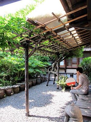 Another extremely simple arbor, a two-post lean-to against side of building with a climbing vine going up far post Bamboo In The Garden, Simple Arbor, Bamboo Arbor, Side Of Building, Lean To Conservatory, Bamboo Projects, Side Garage, Curved Pergola, Pergola Plans Design