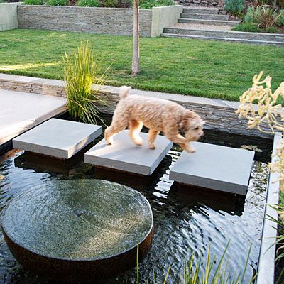 Water crossing  Bluestone pavers traverse this water feature in Alamo. The designer attached them to concrete pillars built into the bottom; each one is cantilevered 4 inches out from its pillar. The dark Mexican pebbles lining the pool and the dark-hued pillars make the water more reflective. The fountain in the foreground is made from an old millstone, polished smooth on top. Pond Backyard, Bluestone Pavers, Modern Water Feature, Backyard Pond, Outdoor Water Feature, Pond Ideas, Garden Walkway, Water Features In The Garden, Ponds Backyard