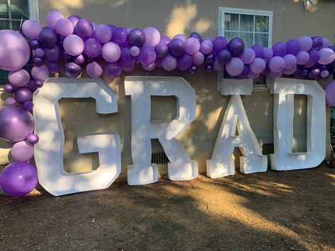 purple ballon arch with big cardboard letters spelling grad for graduation Purple Black And White Graduation Party, Purple Graduation Party Ideas Decoration, Purple Graduation Decorations, Purple And White Graduation Party, Purple And Silver Graduation Party Ideas, Purple And Black Graduation Party, Graduation Party Decor Purple, Pink And Purple Graduation Party, Purple Grad Party Decorations