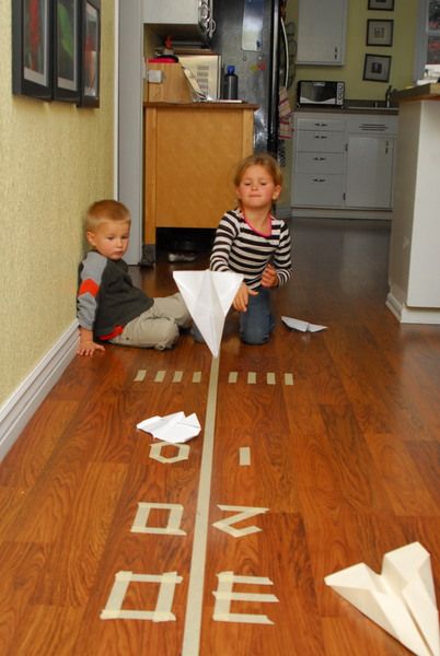 Paper Plane Tape Landing Strip - Meaningfulmama.com Paper Airplane Game, Provocations Reggio, Airport Theme, Plane Games, Airplane Games, Games Indoor, Landing Strip, Diy Carnival, Airplane Crafts