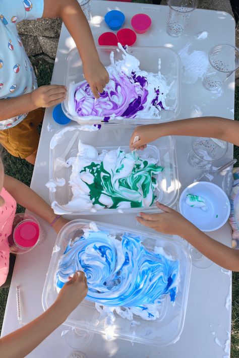 Children’s hands stirring blue and green liquid watercolors into white shaving cream, creating a swirling pattern during a sensory activity. Shaving Cream Play, Shaving Cream Sensory Play, Shaving Cream Activities, Shaving Cream And Food Coloring, Potions For Kids, Slime With Shaving Cream, Shaving Cream Art, Sensory Activities For Preschoolers, Water Table Activities