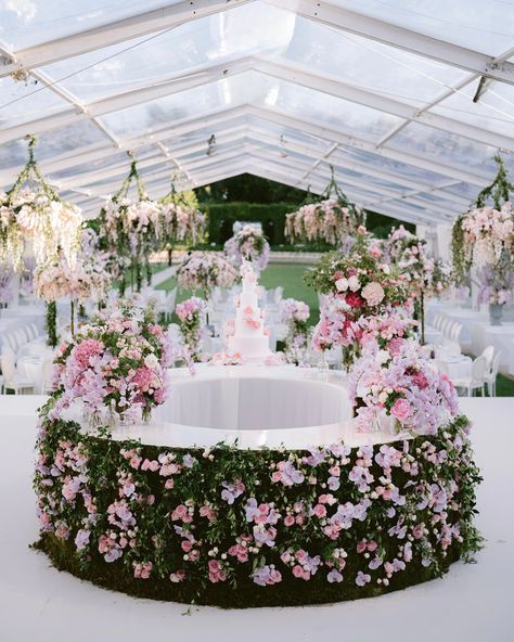 The wedding cake table is adorned with florals and greenery, featuring an elegant pink wedding cake | wedding cake, wedding cake ideas, floral wedding cake, wedding cake design, floral wedding cakes, flower cake, white wedding cake, floral cake, wedding cake table, elegant wedding cake, floral wedding theme, wedding aesthetic, floral ideas, flower design, wedding flowers, wedding ideas, wedding décor, wedding decorations, wedding florals, wedding reception decor, wedding reception ideas #wedding Floral Cake Wedding, Cake Ideas Floral, Floral Wedding Theme, Flower Design Wedding, Wedding Cake Floral, Alfresco Wedding, The Wedding Cake, Floral Wedding Cake, Garden Weddings Ceremony