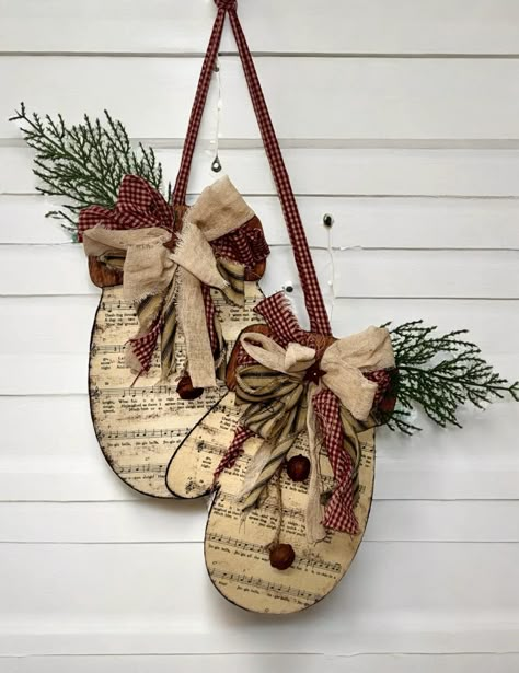 Winter wooden mittens covered in Christmas music sheet for wall or door decor.  Mittens are grunted up and come attached, embellished with a fabric bow in wine, tan and black tones,  with Christmas greenery, and rusty bells with a fabric hanger.  Measures approximately 12" tall x 8" wide x .25" thick. Primitive Country Christmas, Wooden Christmas Crafts, Christmas Sheet Music, Handmade Christmas Crafts, Christmas Decorations Diy Outdoor, Christmas Greenery, Christmas Wood Crafts, Christmas Decorations Rustic, Primitive Christmas