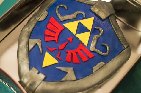 Legend of Zelda Hylian Shield Cake by Christina Guan Zelda Shield Cake, Zelda Cake Ideas, Legend Of Zelda Cake, Zelda Food, Zelda Recipes, Birthday Cake Ideas For Boys, Zelda Crafts, Zelda Hylian Shield, Cake Ideas For Boys