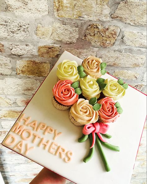 Cream, beige and light pink cupcakes placed on a white board with beige writing saying “Happy Mothers Day”. Made to look like a bunch of flowers with stems and leaves in green and a pink bow. Mothers Day Cupcake Bouquet, Flower Bouquet Cupcakes, Mother’s Day Pull Apart Cupcakes, Mother’s Day Bento Cake With Cupcakes, 7 Cupcake Bouquet, Cupcakes Bouquet, Bouquet Cupcakes, Mother’s Day Cupcake Flower Bouquet, Cupcake Flower Bouquets