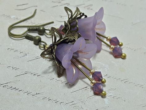 LILAC HIPPIE FLOWER EARRINGS  ▪️▪️▪️▪️▪️▪️▪️️▪️▪️▪️▪️▪️▪️ These pretty lilac purple vintage inspired floral earrings are made with super cute Lucite fairy flowers. They have matching coloured Swarovski crystals in cyclamen opal added for sparkle when they move. They are finished with antique bronze fish hook ear wires and ornate bead caps. They are very light weight and are perfect for special occasions, festivals and bridesmaids yet cute enough for everyday wear.  💜MATERIALS *Lucite Flowers  * Lilac Earrings, Fairy Earrings, Vintage Inspired Earrings, Hippie Flowers, Gothic Earrings, Bronze Earrings, Hippie Earrings, Purple Earrings, Lilac Flowers