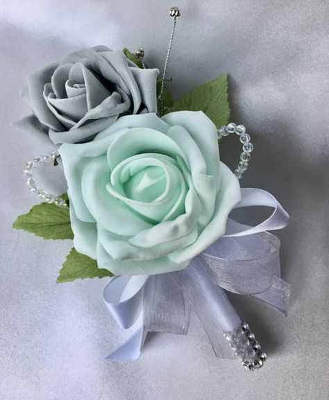 Double Mint Green and Grey Rose Buttonhole with Diamantes and Crystals This stunning buttonhole has been made using one artificial mint green and one grey rose. I have then incorporated crystal loops and a diamanté spray. The handle has then been wrapped in white satin ribbon with