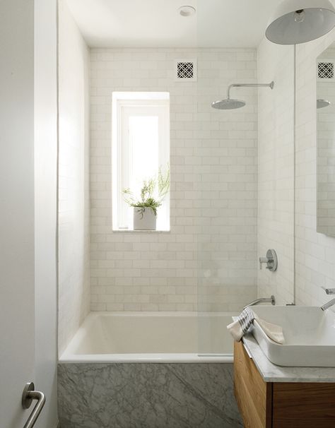 guest bath. All of the apartment’s fixtures are by Kohler, including the kitchen sink and faucet as well as the Tea-for-Two bathtub, Vox square sink, and Catalan mirror in the bathroom. The Thassos marble subway tile is by Ann Sacks. Bathtub Shower Combo, Bathroom Tub Shower, Bathtub Remodel, Bathroom Tub, Tiny Bathrooms, 아파트 인테리어, Tub Shower Combo, Small Bathroom Design, Minimalist Bathroom