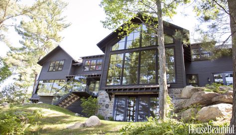 Hepfer designed her family's cottage in the Muskoka Lakes region north of Toronto.Elevated on a 60-foot setback, the L-shaped cottage has black siding to help it disappear into the trees. "If you're on the water, the house vanishes against the darkness," Hepfer says. Cottage House Exterior, Ontario Cottages, Muskoka Cottage, Sofa Santai, Lake Houses Exterior, Farmhouse Exterior Design, Modern Lake House, Small Cottage Homes, Cottage Exterior