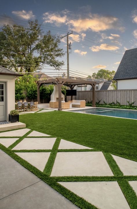 Featuring luxurious grass-cut concrete pavers, a serene grass-line pool, inviting outdoor fireplace, and chic al fresco dining area, our design seamlessly blends sophistication with Southern charm. Dive into poolside elegance and elevate your outdoor living experience today. #HamptonsPool #HamptonsGarden #GrassCutConcretePavers #OutdoorLiving #PoolsideParadise #AlFrescoDining #OutdoorDesign #DallasLandscape Concrete And Fake Grass Backyard, Pool With Grass Surround, Grass And Pavers Backyard Ideas, Grass And Pavers, Fake Grass Backyard, Walk In Pool, Hamptons Pool, Backyard With Pool, Small Yard Design