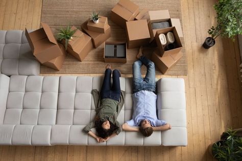 Couple laying on couch with unpacked cardboard boxes on floor Laying On Couch, Fun Couple Games, Flat Landscape, Government Grants, Leo Dicaprio, Couple Games, Sketch Comedy, First Time Home Buyers, Paramount Pictures