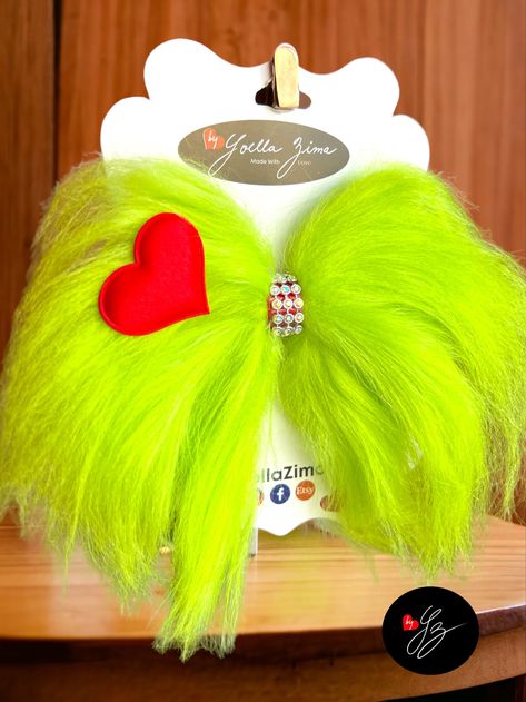 "One mean hair bow inspired by the beloved Christmas grump, for kids or adults. This hair bow has already been to the stylist, it is pre-treated with hairspray to look clean and shapely under all conditions  💚 5\"H x 6\"W 💚 Green fur fabric 💚 Alligator clip 2.5\" (if you need  1.75\" leave a note). 💚 Treated with hair spray  💚 Rhinestones  💚 Made with love and patience Never leave children unattended with the bow.  If you have any question or request let me know please and thank you for supporting my small business." Diy Christmas Hair Accessories, Grinch Hair, Whoville Costumes, Pom Pom Hair Ties, Crafts 2024, Holiday Hair Bows, Whoville Christmas, Christmas Hair Accessories, Green Fur