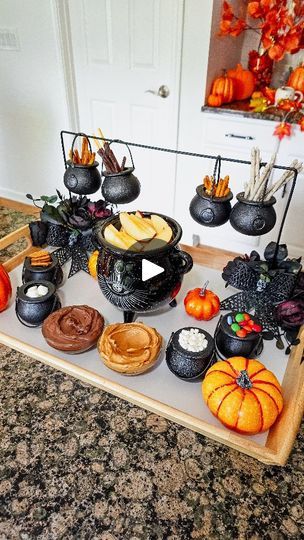 10K views · 7.8K reactions | Cauldron Serving Rack DIY! 🧙‍♀️🪄 This was way easier and so much fun to make than I even envisioned!

All you need is:

Metal hanger
Mini plastic cauldrons
Floral foam square
Decorative flowers/leaves/bows of choice

How to:

Remove the hook part from the hanger and bend the hanger out to make a rectangle frame. Slide in the mini cauldrons onto the frame (you can also use black hooks or paper clips to hang the cauldrons after you position the frame). Insert the ends of the frame into the floral foam; decorate/cover the foam with fake leaves, flowers, bows (I used black silk leaves, roses, and skull bow from dollar store). Set the Cauldron Rack on serving tray or large wooden cutting board, add more cauldrons/ramekins, fill/serve with your desired treats, and Mini Cauldron Decoration Ideas, Apple Dips, Cubicle Halloween Decorations, Marshmallow Bits, Diy Serving Tray, Halloween Party Activities, Fake Leaves, Halloween Living Room, Hocus Pocus Party