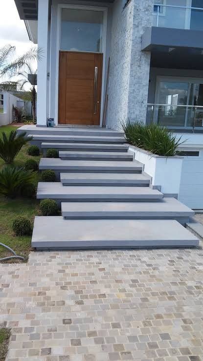 Keep the design sleek and simple with clean lines, concrete steps, and minimalistic plantings like small topiaries or grasses. Sloped Steps Landscaping, Side Stairs Entrance Outside, Outdoor Staircase Ideas, Steps Design Outdoor, Floating Stairs Outdoor, Outdoor Staircase Design Entrance, Outdoor Stairs Concrete, Exterior Stairs To Front Door, Entrance Steps Design