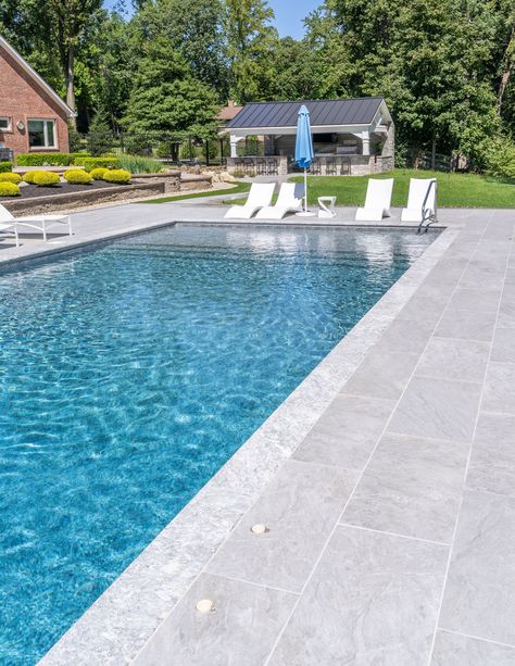 Dive into the beauty of this pool, meticulously adorned with our best-selling Pietra Grey marble copings paired flawlessly with the subtle veining of our Moon porcelain pavers. This combo is nothing short of iconic, where the striking white veining of the Pietra Grey marble harmoniously complements the understated veining of the pavers. Together, they create a poolside panorama that radiates elegance, sophistication, and timeless beauty. Marble Pool Coping, Pool Pavers And Coping, Pool Coping And Tile, Pool Scapes, Portugal Garden, Pietra Grey Marble, Portugal House, Pool Makeover, Inground Pool Landscaping