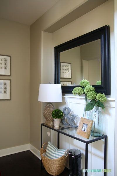 Glass and black side table with black mirror above it and fresh flowers on the side table. Glass Console Table Decor Entryway, Glass Entry Table Decor, Glass Entry Table, Entry Console, Life On Virginia Street, Entry Mirror, Iron Console, Console Entryway, Fall Entryway