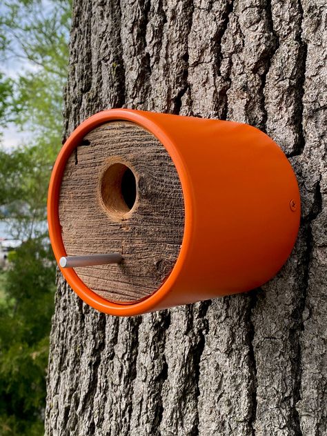 This orange handcrafted birdhouse features a deeper depth, durable vinyl tube with surface and edges sanded smooth and 4 coats of orange paint applied. Adding a one-of-a-kind kind, upcycled rustic charm, each end features circular cut reclaimed historic Michigan barnwood. A sleek aluminum rod allows birds to perch at entry. Moisture relieving holes are at the bottom. The house mounts to a wall or tree by a shou sugi ban wood burn treated back plate with included stainless-steel screw. Once the plate is mounted to the wall, the house slides over the back plate and is secured at each side with color-matched, painted screws. This allows for simple seasonal removal and cleaning as well. Specs: Tube = 4-3/4" deep x 5" diameter vinyl End Caps = 4-1/2" wood Entry = 1-1/2" hole with sanded edges B Sugi Ban Wood, Mcm Minimalist, Wood Bird House, Cool Bird Houses, Modern Birdhouses, Homemade Bird Houses, Bird Houses Ideas Diy, Handmade Birdhouses, Bird House Feeder