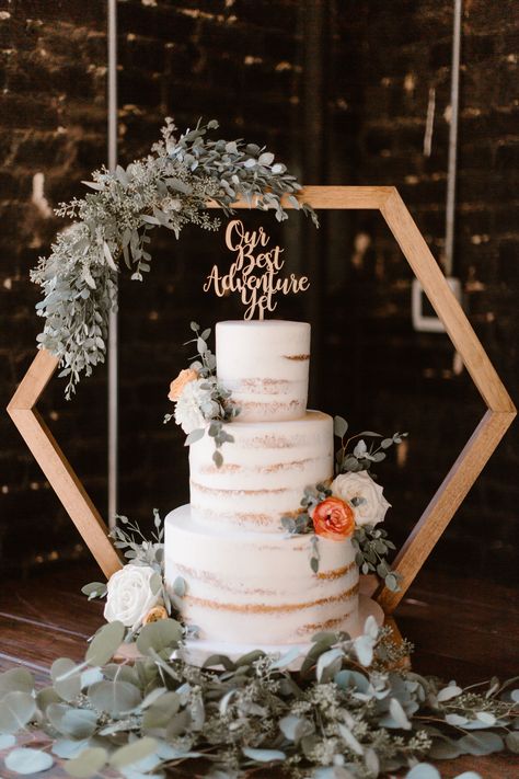 If you're looking for a modern twist on a classic wedding treat, this show-stopping three-tier naked white wedding cake on a geometric cake stand is sure to be the highlight of your special day. Not only will this gorgeous cake be a showstopper, it will also add a touch of sophistication to the celebration with its intricate diamond design. With layers of tender buttercream and moist white sponge, this cake is sure to be a hit with your guests at the reception. Erin Morrison Photography Wedding Cakes Stands Ideas, Modern Boho Wedding Backdrop, Hexagon Wedding Cake Topper, Cake Stand Backdrop, Wedding Cake Arch Stand, Octagon Centerpiece Wedding, Honeycomb Wedding Decor, Wedding Hexagon Centerpieces, Hexagon Table Centerpieces