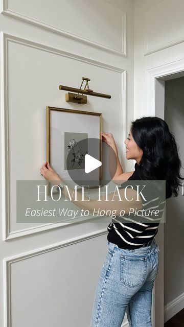 Lisa Chun on Instagram: "The infamous tape hack is amazing for not having to measure the distance between hooks for a frame… but have you tried *flipping the tape backwards* and lining up the holes again so the sticky side faces the wall?? Now you can just eyeball and press the tape to the wall exactly where you want it and it’ll be in the perfect spot! Send this reel to a friend who haaates hanging pictures and you’ll be their hero. 😉

BONUS: This gorgeous bestselling frame is on MAJOR sale right now and this battery operated picture light requires no wires and makes it look so elevated!! Like and comment “SHOP” for links!

Artwork by the incredible @kesiafinleyart ❤️" Wall Light Hack, Picture Hanging Ideas, Picture Frame Light, Hanging Picture Frames, Command Strips, Picture Hanging, Wall Gallery, Battery Operated, Hanging Pictures