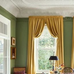 Umberto on Instagram: ""In the sitting room, curtains in yellow faux silk from Blendworth Interiors and walls in Farrow & Ball’s ‘Yeabridge Green’ are the backdrop for a buttoned sofa in cotton velvet, dyed to match the paint colour. The cushions are in the same ‘Tree Poppy’ chintz from Colefax and Fowler as the armchairs opposite. On the Dutch colonial rosewood, ebony and bone side table next to the sofa, a Turkish ceramic lamp is partnered by a silk ikat lampshade by Gregory Mellor Design Elsa Young" @houseandgardenuk @gregory.mellor.design #inspire_me_home_decor #sittingroom #interiordesigner #interiorstyling" Sitting Room Curtains, Yeabridge Green, Ikat Lampshade, Yellow Curtains Living Room, Button Sofa, Colefax And Fowler, Yellow Curtains, Yellow Living Room, Dutch Colonial