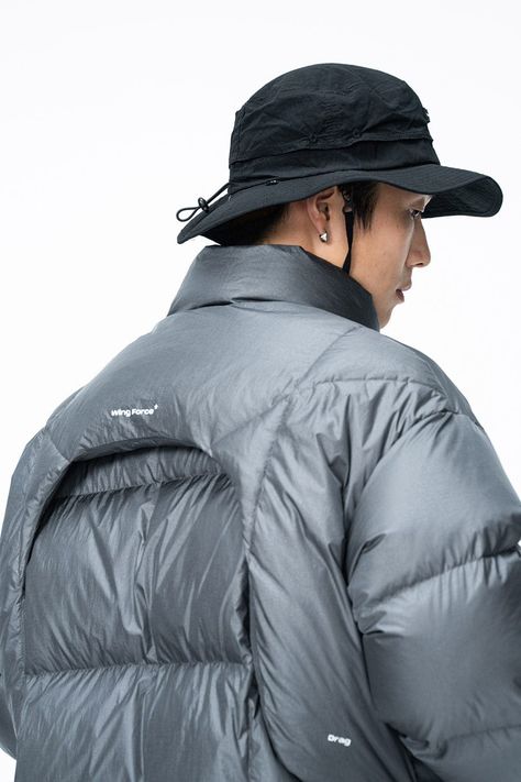 Inspired by the aerodynamic spoilers of racing cars, the Wing Force Down Jacket is a futuristic marvel in apparel design. Its silver-gray color scheme embodies a sleek, modern aesthetic. The jacket is thoughtfully equipped with two waterproof zippered pockets on the front, ensuring practical storage options while maintaining style. Filled with 286g of high-quality white duck down, it promises exceptional warmth. The fabric is also treated for water resistance, making it a versatile choice for di Tech Clothing, Technical Clothing, Grey Color Scheme, The Wing, Jackets Men Fashion, Futuristic Fashion, Practical Storage, Hooded Parka, White Duck