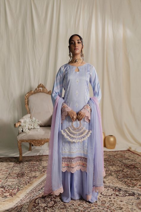 Lace-enhanced shirt paired with an ijar trouser finished with gota lace edge, creating a captivating ensemble that exudes timeless charm. The dupatta comes in pinkish-purple and light blue color. Elevate your style with this sophisticated and fashion-forward statement. Be it a festive party or a wedding night, these luxury silk dresses are perfect choice for any event. Shirt Fabric: Luxury Silk Pant Fabric: Pure Raw Silk (PK) Work Technique: Digital Printed detailed with Handwork Embellishments Silk Pant, Trousers Details, Pinkish Purple, Silk Dresses, Silk Trousers, Coral Peach, Luxury Silk, Statement Shirt, Silk Pants