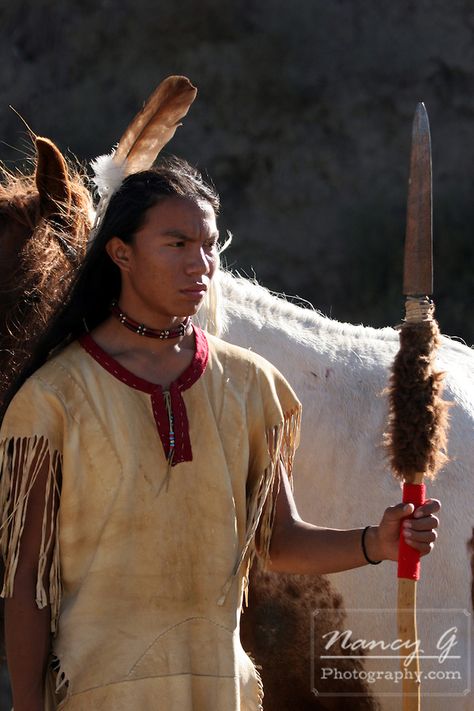 A Native American Indian boy wearing a feather standing next to a horse holding a spear with buffalo hide on it Lighting Reference, Native American Men, Indian Boy, American Men, Selena Quintanilla, Boys Wear, Native American History, Teenage Boys, My Heritage