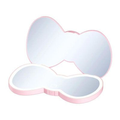 Be an icon with the Hello Kitty® Bow Compact! Modeled after the iconic Hello Kitty bow silhouette, this LED compact mirror features a soft sensor button that reveals her supercute face. Tap to toggle through three light color temperatures for the perfect lighting. Enjoy energy-saving features like auto shutoff for extended use. Shine on and be an icon! | IMPRESSIONS VANITY · COMPANY Hello Kitty Bow LED Compact Mirror w / Soft Touch Button, Double Sided Cute Travel Makeup Mirror | Wayfair | Home Travel Makeup Mirror, Face Mirror, Hello Kitty Bow, Portable Mirror, Impressions Vanity, Makeup Vanity Mirror, Hello Kitty Accessories, Flawless Makeup Application, Handheld Mirror