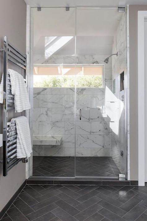 Slate herringbone pattern floor tiles in a transitional bathroom includes a seamless glass shower with large white and gray marble staggered wall tiles. Pattern Floor Tiles, Dark Tile Floors, Slate Bathroom, Design Interior Baie, Grey Bathroom Floor, Dark Gray Bathroom, Herringbone Tile Floors, Marble Bathroom Floor, Shower Wall Tile