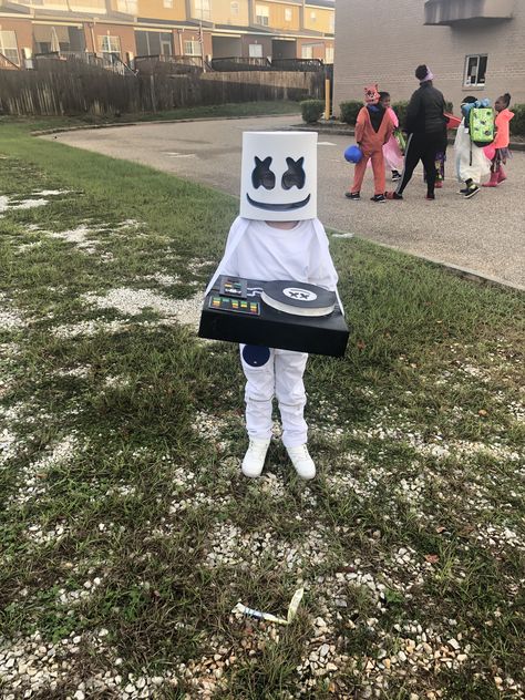 DIY Marshmello halloween costume. I put together this Halloween costume. We got the most compliments on it! Super easy!! White Moto jeans, white T-shirt (had to add the jacket because it was so cold...brrr), light up shoes, and head. I made the DJ turn table out of a cardboard box. Shoes, head, and turntable all light up blue when turned on. Everything was pieced together from items purchased on amazon. Dj Marshmello Costume, Dj Turn Table, Marshmello Costume, Marshmallow Costume, Marshmallow Man Costume, Diy Costumes Men, Marshmello Dj, Easy Diy Halloween Decorations, Diy Halloween Costumes For Kids