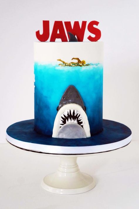 Mad asking to do a JAWS cake for a Horror Film fanatic and writer. Once the “I want the head of the shark” idea went out of the window because of cost constraints I proposed to recreated that famous 70’s JAWS poster….come on! who isn’t still... Jaws Cake, Shark Themed Cakes, Cake Shark, Jaws Party, Jaws Poster, Shark Printables, Horror Cake, Shark Week Party, Shark Birthday Cakes