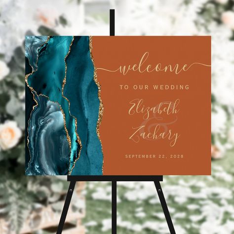 This elegant modern wedding welcome sign features a teal watercolor agate design trimmed with faux gold glitter. Easily customize the gold-colored text on a burnt orange background, with the names of the bride and groom in handwriting calligraphy over a large ampersand. (If you would like this sign in a different size, please be sure to avoid choosing any of the other "standard sizes," which may distort the design. Instead, scroll down to the "Choose your own size" option, and leave the "link" i Teal Burnt Orange And Gold Wedding, Burnt Orange And Teal Wedding Decor, Teal And Orange Wedding Decor, Teal And Burnt Orange Wedding Arch, Teal And Copper Wedding Decorations, Burt Orange And Teal Wedding, Teal And Burnt Orange Wedding, Fall Wedding Teal And Orange, Rusty Orange Wedding