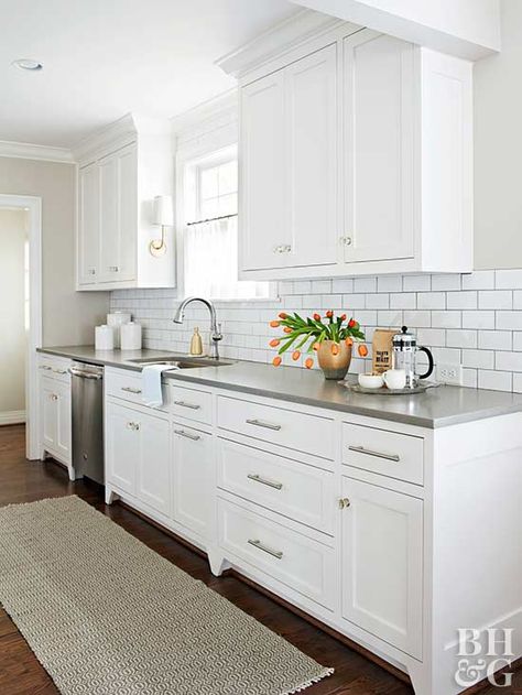 Preserving the galley-style kitchen layout eliminated the need to move plumbing or electric wiring—a budget-saver that allowed for new hardwood floors, cabinets, finishes, and appliances. A subway tile backsplash reflects light throughout and creates clean lines with newly painted cabinets. Stainless-steel appliances and drawer pulls keep the kitchen contemporary and ready for cooking. Cape Cod House Interior, White Galley Kitchen, Small White Kitchens, Galley Kitchen Design, Galley Kitchen Remodel, Galley Style Kitchen, Diy Kitchen Renovation, White Kitchen Design, Galley Kitchen