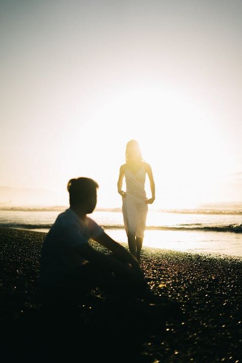 Silhouette Of Man Sitting On Seashore While Looking At Woman In White Dress Walking Towards Him Man Taking Picture Of Woman, Scary Fairy, Woman In White Dress, Hand Silhouette, Woman In White, Man Sitting, Wonderful Picture, Wedding Engagement Photos, Men Beach