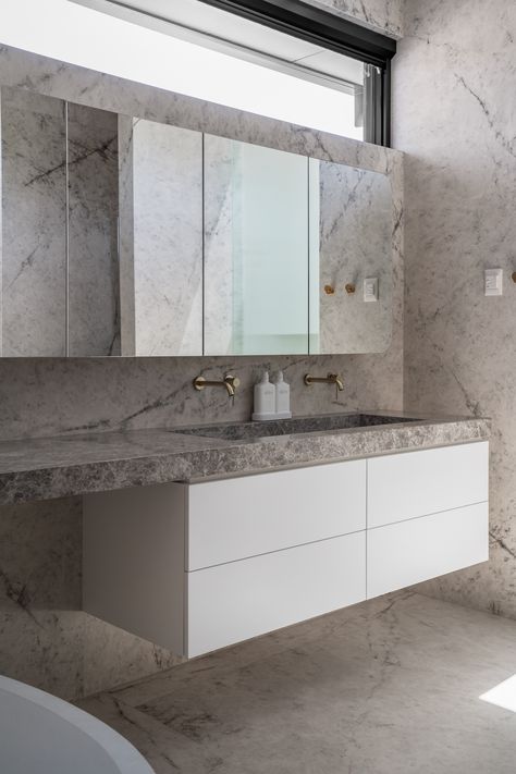 Tundra Grey Marble vanity top with a bespoke marble sink. Its exquisite beauty effortlessly complements the elegance of gold tap ware and porcelain wall cladding. Crafted to perfection, this marble ensemble adds a touch of luxury to this breathtaking ensuite bathroom. For more bespoke marble benchtops in #Adelaide, contact us! www.uniqstone.com.au E: estimating@uniqstone.com.au | P: (08) 8266 2280 Stone Vanity Top | Tundra Grey Uniq Stone Deluxe Natural Stone Stone Wall Cladding | Sub Ze... Tundra Grey Marble, Stone Vanity Top, Stone Vanity, Gold Taps, Stone Wall Cladding, Marble Sink, Marble Vanity, Marble Sinks, Ensuite Bathroom