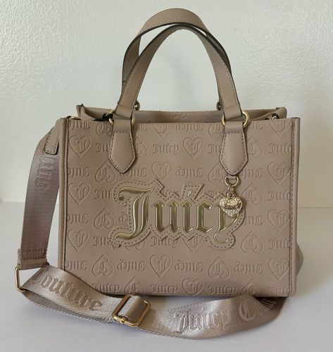 Juicy Couture Upgrade U Mini Tote Condition: New with tags Color: Cafe * Tan / Cafe faux leather w/ debossed Juicy logos * Gold tone hardware and front heart charm w/ crystal accents * Flat double carry handles w/ 5” drop * Adjustable crossbody strap w/ 23” drop (not detachable) * Open top w/ 1 zip pocket and 2 slip pockets * Measurements: 9.5”W x 7.75”H x 5.5”D MSRP $99.00 Cafe Gold, Pretty Backpacks, Juicy Couture Clothes, Fav Products, Candle Pedestal, Dream Bags, Juicy Couture Purse, Luxury Bags Collection, Juicy Couture Accessories