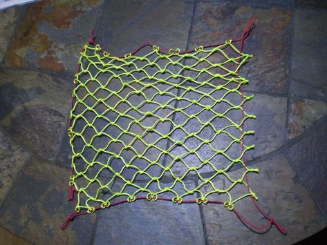 DIY cargo net that is 14 inches on each side. The yellow cord is mason's line. The red rope is 1.8 mm 100lb test tent guy line. I use this to suspend my shoes off the ground. Camping Tents Ideas, Paracord Net Diy, Climbing Net Diy, Cargo Net Hang Out Spot, Diy Cargo Net, Crochet Pocket Net Bag, Backpack Design Concept, Bike Touring Packing, Emergency Go Bag